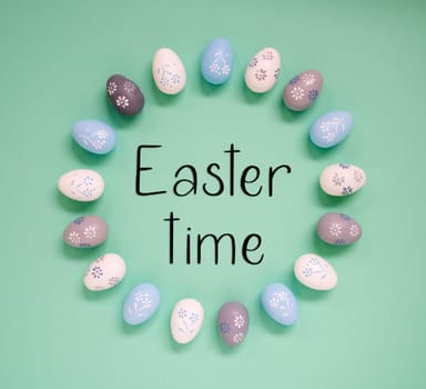 Flat Lay With English Text Easter Time. Easter Egg Arrangement, Decoration And Ornament. Light Green Paper Background