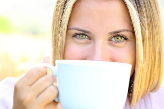 Front view close up of a happy teen with beauty eyes holding coffee mug looking at camera