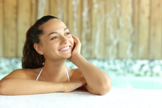 Happy woman in spa pool thinking looking at side