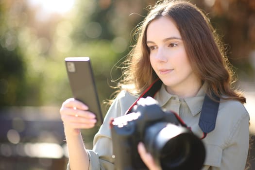 Photographer pairing smart phone app with dslr professional camera outdoor