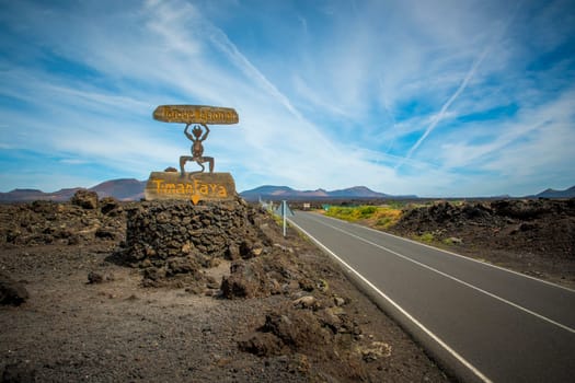 Timanfaya, Lanzarote, Spain, March 2023: View on the entrance sign and road of Timanfaya National Park on Lanzarote, Canary Islands. The El Diablo symbol was designed by Cesar Manrique.