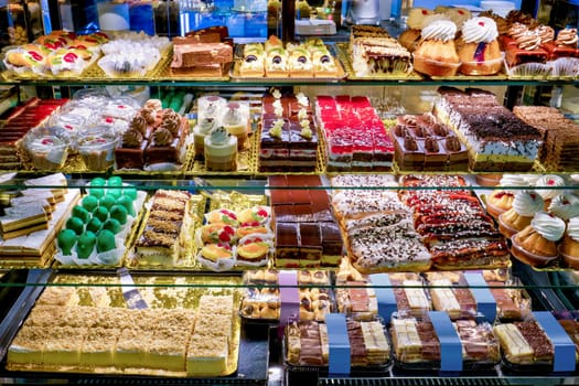 Showcase with four shelves full of various tasty and beautifully colored cakes