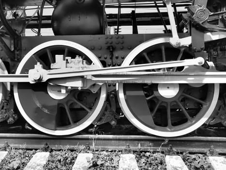 Retro train two wheels. Sleepers and rails, mechanisms, pistons and guides. Locomotive of the 19th early 20th century with a steam engine. Vintage style. Black - white photo. Beautiful card