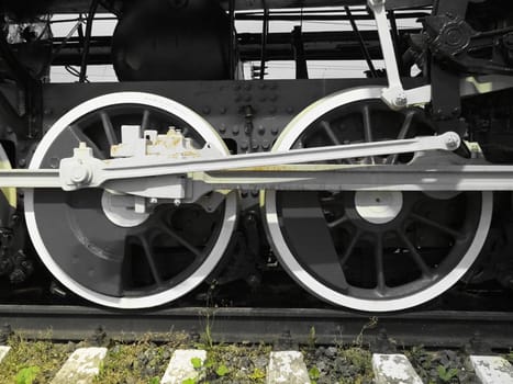 Retro train two wheels. Sleepers and rails, mechanisms, pistons and guides. Locomotive of the 19th early 20th century with a steam engine. Black and white wheels with green grass. Vintage style.