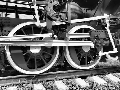 Retro train two wheels. Sleepers and rails, mechanisms, pistons and guides. Locomotive of the 19th early 20th century with a steam engine. Vintage style. Black - white photo. Beautiful card
