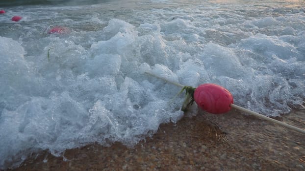 Buoys on a rope near sea water. The buoys are pink restraints to alert people to the depth of the water. Rescue of the drowning. Delimiting a place on a sandy beach between hotels. Wave with bubbles