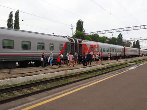 Usman, Lipetsk region, Russia, August 7, 2021. Station of the southeastern railway. The platform with people who got off the train. Russian Railways passenger train. Rails and sleepers. Stopover.
