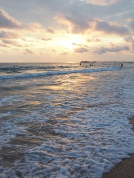 Wave and sunset over sea. Beautiful sunset. Foamy waves roll over the sandy shore. Vityazevo, Anapa, Black Sea. Tourist mecca, health resort. Evening sky. The rays reflect off the water