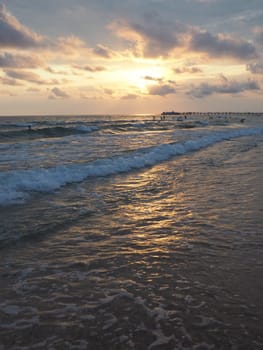 Wave and sunset over sea. Beautiful sunset. Foamy waves roll over the sandy shore. Vityazevo, Anapa, Black Sea. Tourist mecca, health resort. Evening sky. The rays reflect off the water