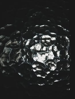 Corrugated glass, rear light source. The play of glare and reflections in a transparent uneven surface. Dark and light abstract asymmetrical multi-illuminated planes. Abstract weird background.
