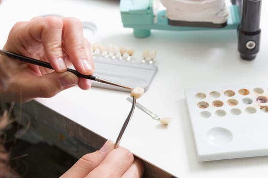 In a dental laboratory,a dental crown is colour-adjusted.