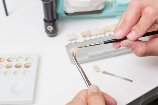 In a dental laboratory,a dental crown is colour-adjusted.