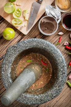 shrimp paste chilli sauce in a mortar stone with Ingredients to cook