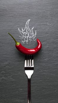red chili pepper with fire and a black graphite background