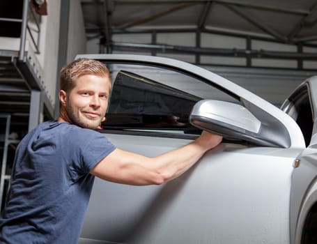 Applying tinting foil onto a car window in a workshop