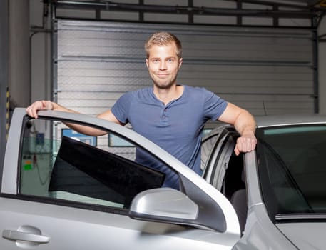 Applying tinting foil onto a car window in a workshop