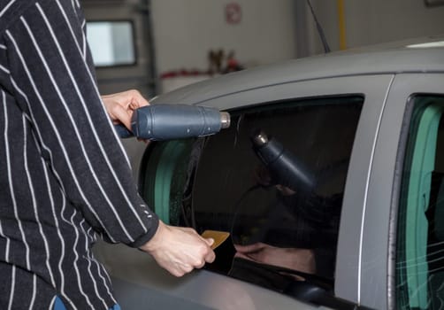 Applying tinting foil on a car window in a garage