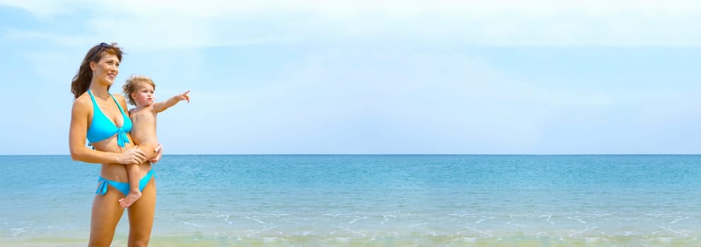 Portrait of young woman with her baby on beach.  Banner, lots of copy space.