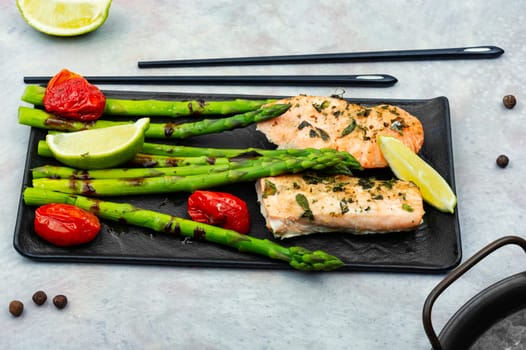 Roasted trout and boiled asparagus on the plate. Top view.