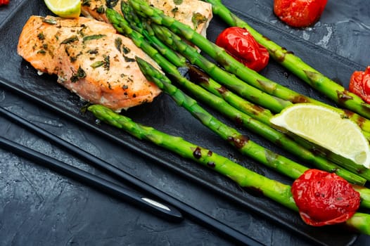 Roasted trout and boiled asparagus on the plate. Top view.
