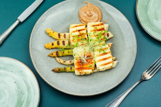 Appetizing appetizer of white asparagus and fried halloumi cheese.