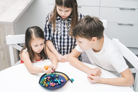 Cloudy looking children of girls and boy looking at girl trying to catch fish bell from fish plate like fisherman. Fish rod games for motor and memory skills. Child development center, day care