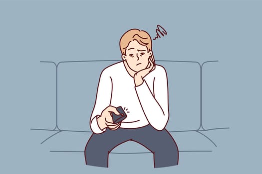 Bored man holding TV remote due to lack of satellite TV channels with interesting shows. Concept frustration and procrastination associated with lack of motivation caused by emotional burnout