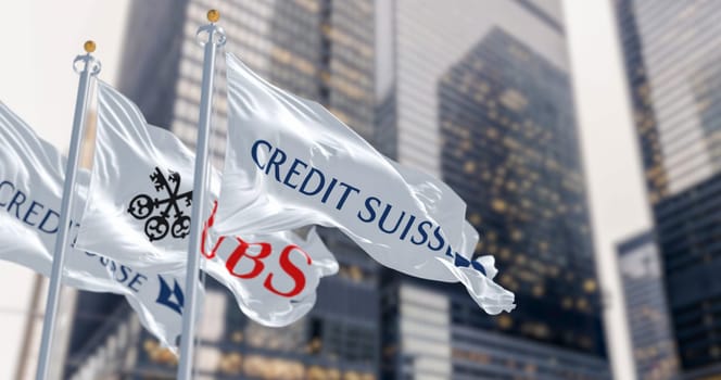 Zurich, CH, March 2023: Flags of Credit Suisse and UBS fluttering in the wind in a financial district. In March 2023, UBS bought Credit Suisse. Illustrative editorial 3d illustration render