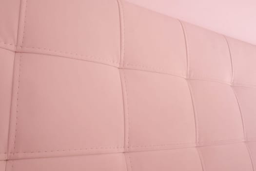 Soft headboard. Upholstery for furniture made of genuine or artificial leather and fabric. Soft headboard against a light wall