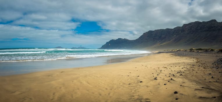 Panorama view on Famara beach on the Canary Island of Lanzarote, with some windsurfing in the far distance