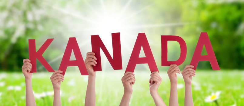 People Or Persons Hands Building German Word Kanada Means Canada. Sunny Green Grass Meadow As Background.