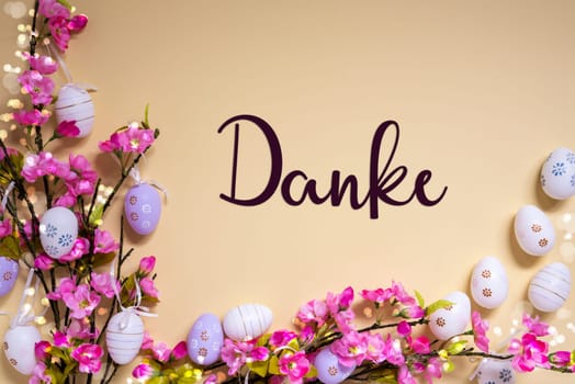 German Text Danke Means Thank You On Beige Background. Pink And Purple, Shiny And Bright Spring Flower Arrangement With Easter Egg Decoration.