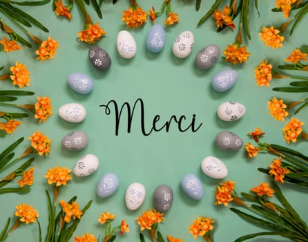 Flat Lay With French Text Merci Means Thank You. Easter Egg Decoration With Orange Spring Flowers. Light Green Paper Background.