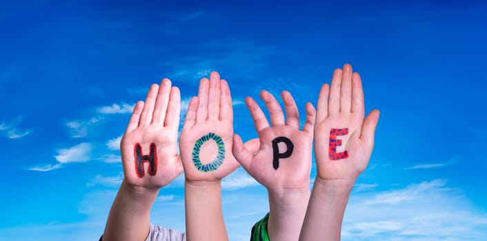 Children Hands Building Colorful English Word Hope. Blue Sky As Background.