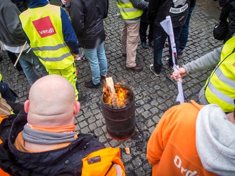 Berlin, Germany - March 06, 2023: Warning strike in front of the gates of the Berliner city cleaning company with orange smoke and waving flags of the union Verdi.