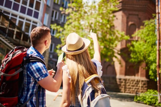 Modern tourists pointing at old building during trip