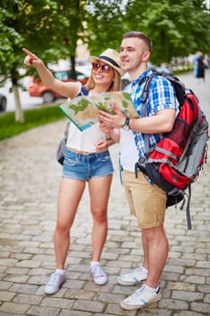 Happy tourists with rucksacks and guide choosing place to visit