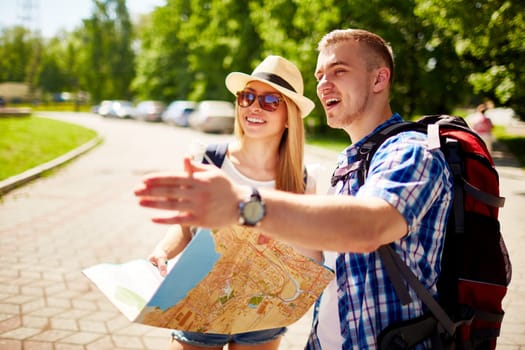 Happy travelers with rucksacks and guide spending vacation in foreign city