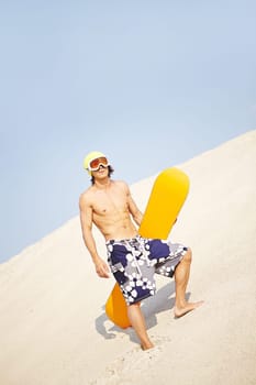 Young man with sandboard standing on beach