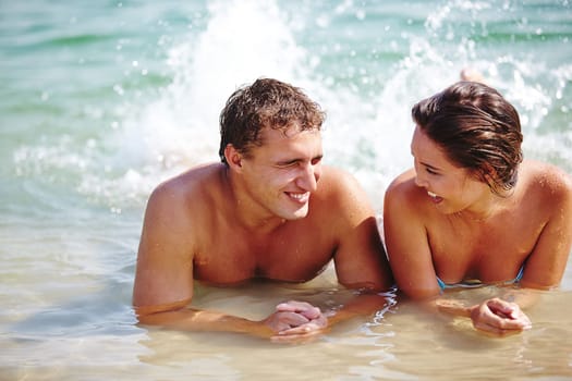 Ecstatic young couple splashing in water during vacations