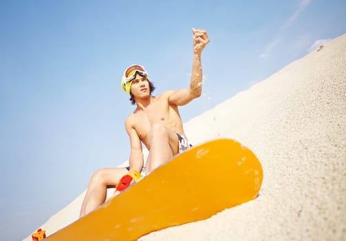 Handsome guy with sandboard sitting on beach