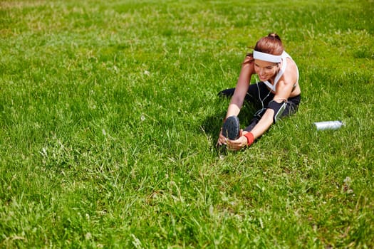 Young sporty woman exercising on green lawn