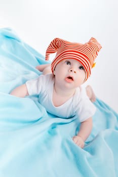 cute toddler in a striped hat on a blue blanket