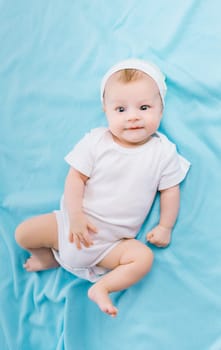 Cute baby in hat lying on a blue blanket