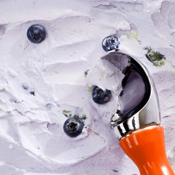 Close Up of Red Handled Scoop Serving Blueberry Ice Cream with Fresh Blueberries Sprinkled on Top