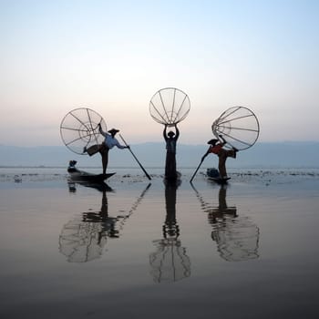 Fishermen at sunrise in the Landscape on the Inle Lake in the Shan State in the east of Myanmar in Southeastasia.