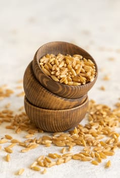 Wooden bowls of raw dry rye grain on white table close up. Healthy alternative low gluten seeds. Protein source for vegan and vegetarian diet.