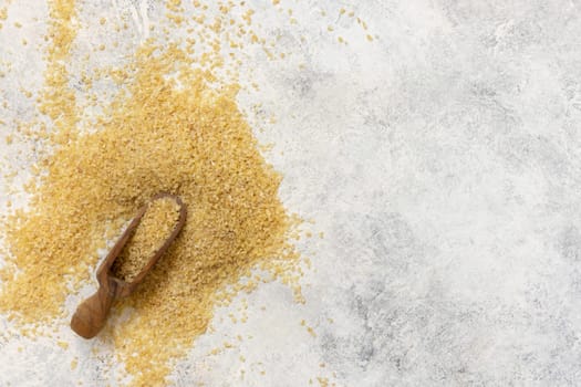 Wooden scoop of Dry uncooked bulgur wheat grain top view, copy space. Vegetarian and Vegan, Mediterranean and Middle Eastern cuisine. Healthy lifestyle