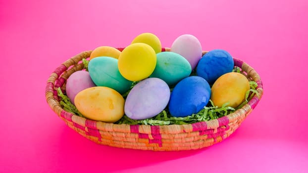 Colorful Easter eggs inside basket  on pink background