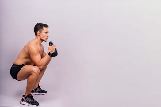 Strong young muscular focused fit man with a big muscles holding heavy kettlebells